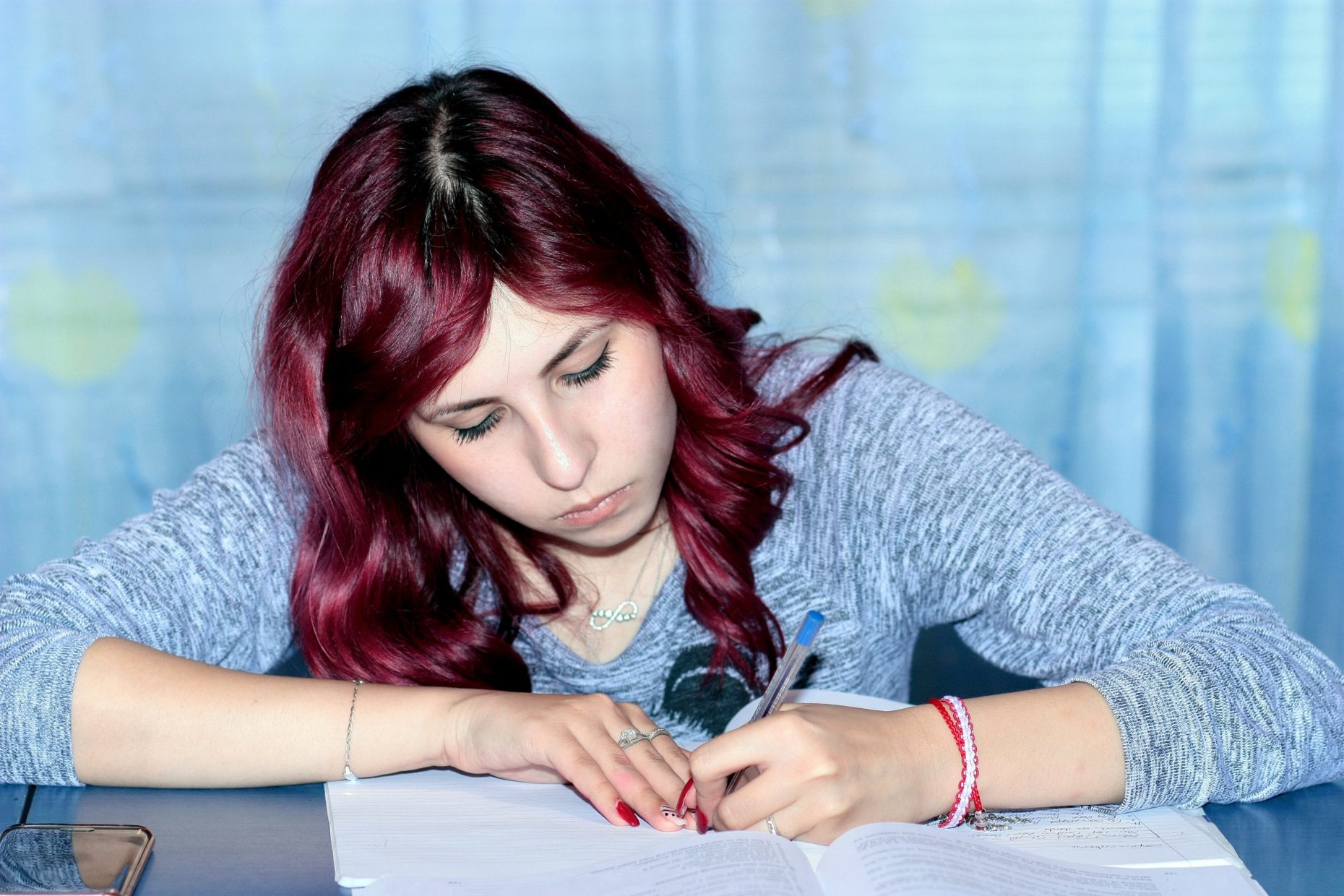 Young woman working on an open written test at her desk